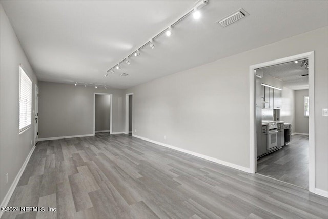 empty room with light wood-type flooring and rail lighting