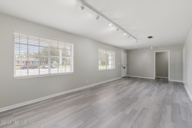 empty room featuring visible vents, light wood-style flooring, and baseboards