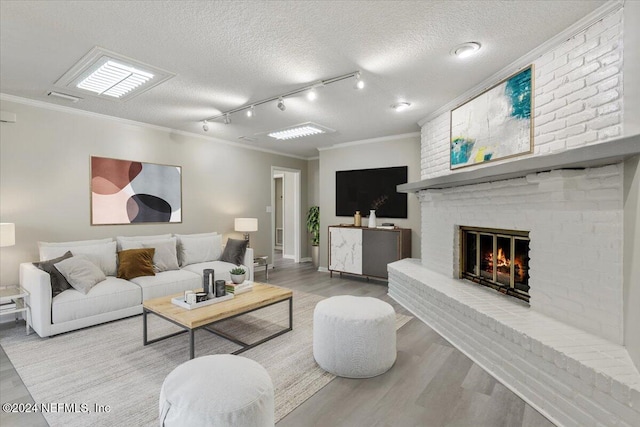 living room with ornamental molding, a fireplace, a textured ceiling, and wood finished floors