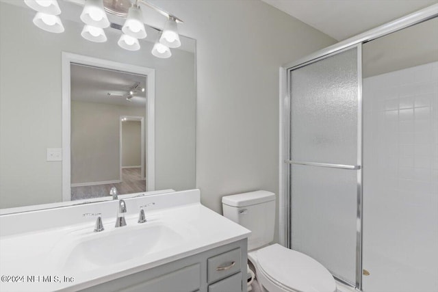 bathroom with toilet, a shower stall, and vanity