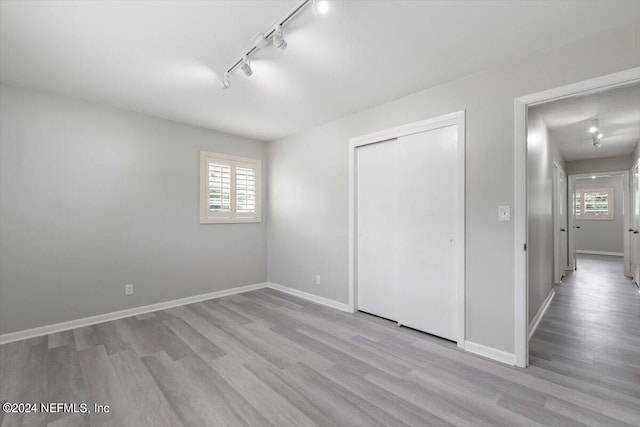 unfurnished bedroom featuring a closet, track lighting, and light wood-type flooring