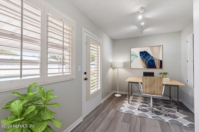 office featuring a textured ceiling, track lighting, dark wood-style flooring, and baseboards