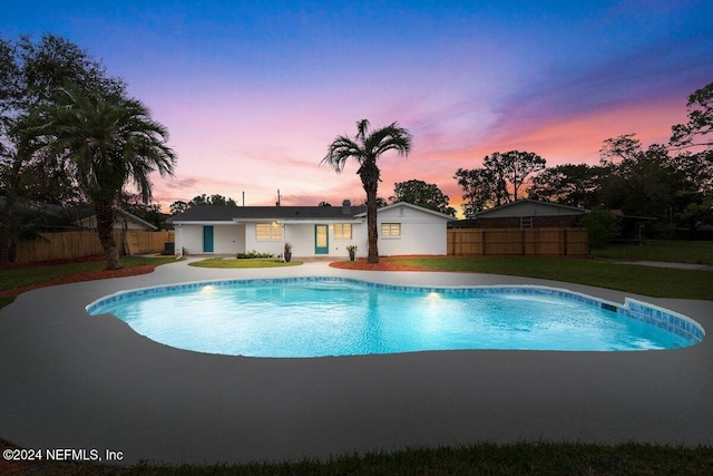 pool at dusk featuring a lawn