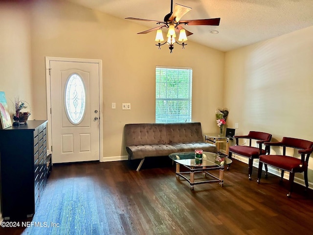 living room with a wealth of natural light, vaulted ceiling, a textured ceiling, and dark hardwood / wood-style flooring