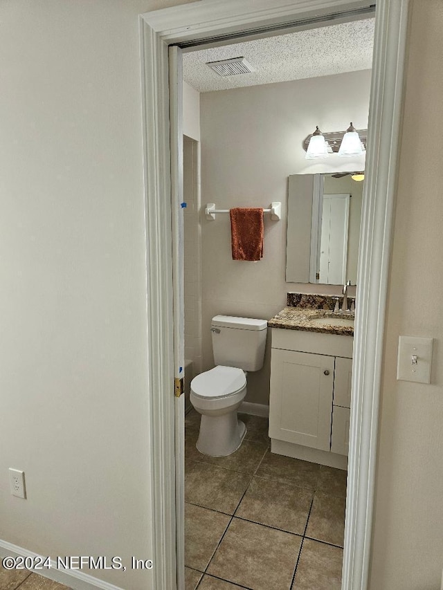 bathroom featuring tile patterned floors, toilet, a textured ceiling, and vanity