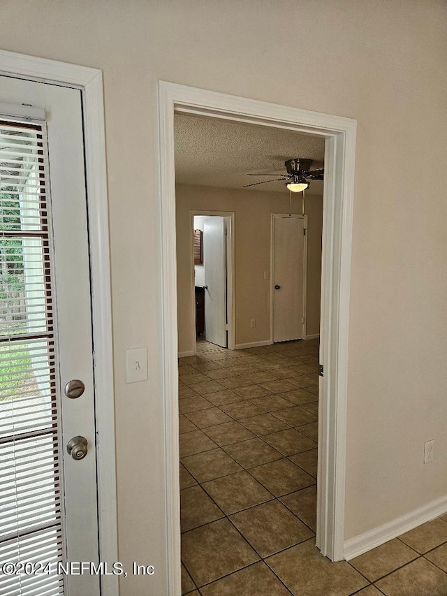 hallway featuring a textured ceiling and tile patterned floors