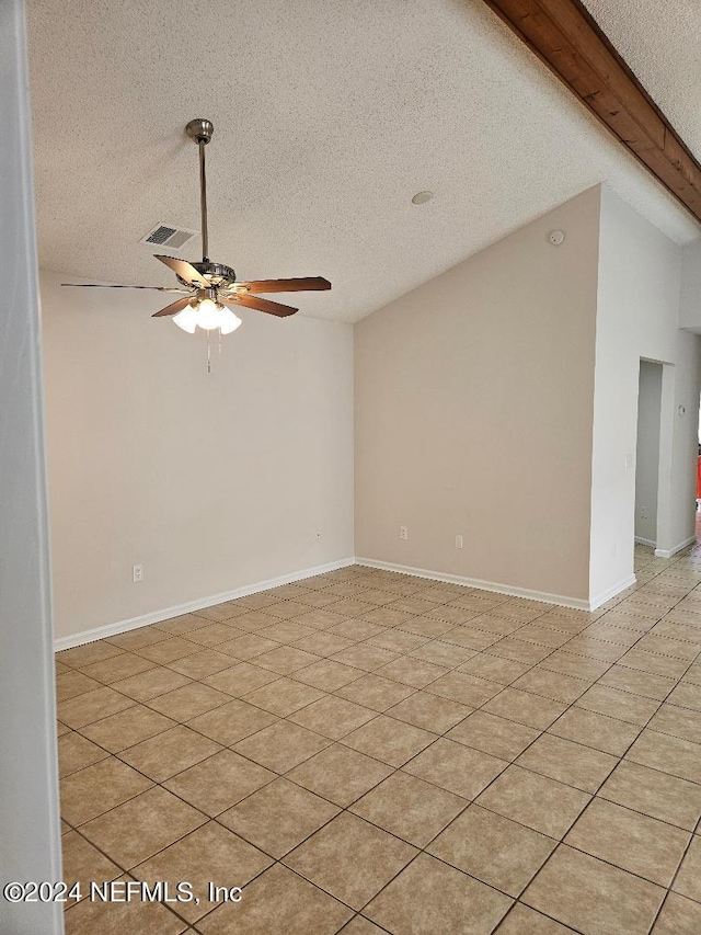 tiled empty room with a textured ceiling, ceiling fan, and vaulted ceiling with beams