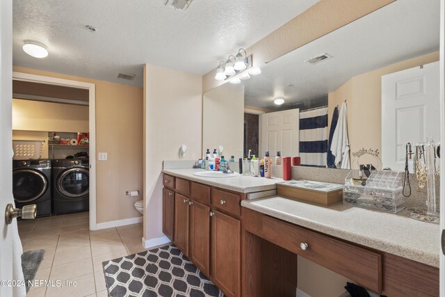 bathroom featuring a textured ceiling, washing machine and dryer, toilet, and vanity