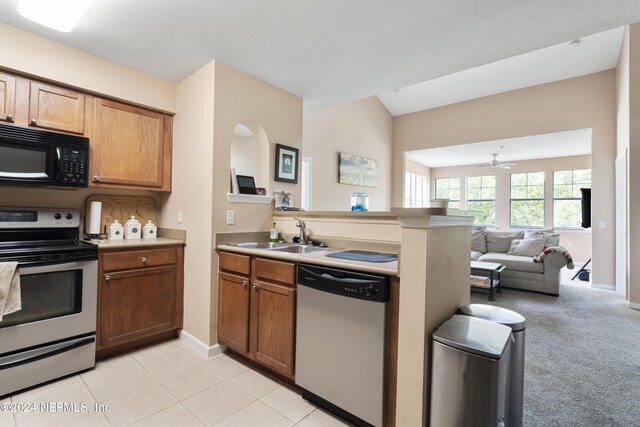 kitchen featuring stainless steel appliances, light carpet, sink, ceiling fan, and a textured ceiling