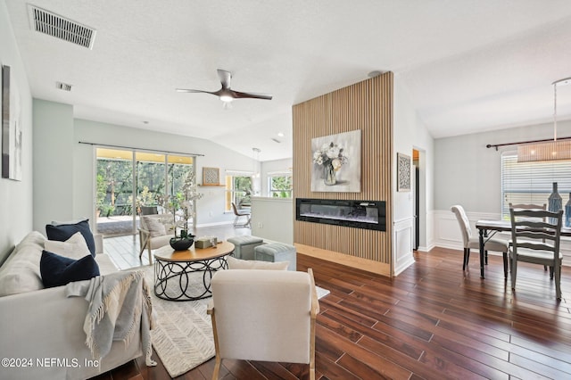 living room with ceiling fan, a textured ceiling, lofted ceiling, and dark wood-type flooring