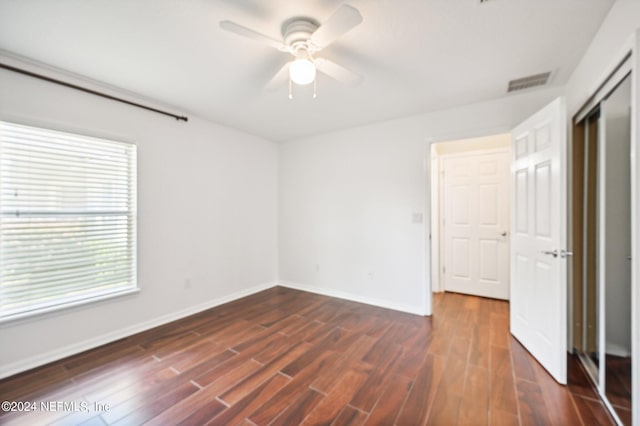 unfurnished bedroom featuring dark wood-type flooring, ceiling fan, and a closet