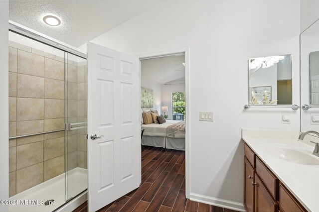 bathroom with lofted ceiling, hardwood / wood-style floors, a shower with door, and vanity