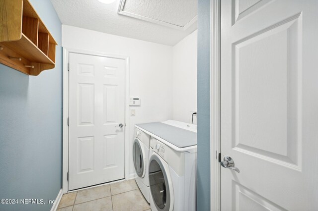 washroom with a textured ceiling, light tile patterned floors, and independent washer and dryer