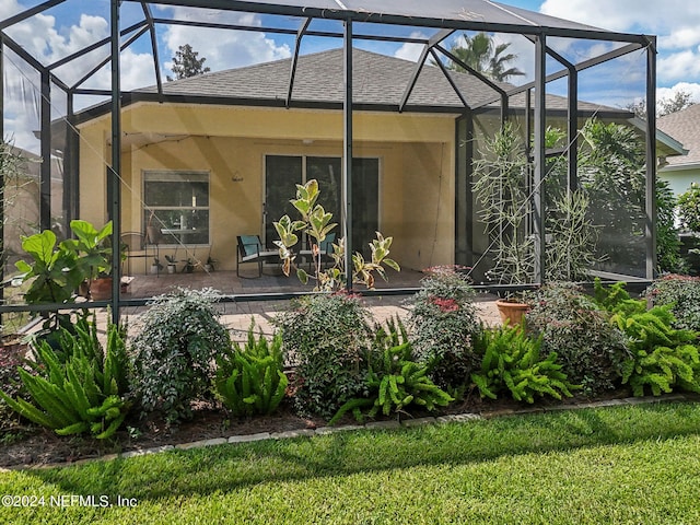 rear view of house featuring glass enclosure and a patio