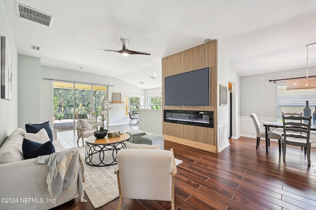 living room featuring vaulted ceiling, a textured ceiling, a large fireplace, ceiling fan, and dark hardwood / wood-style floors