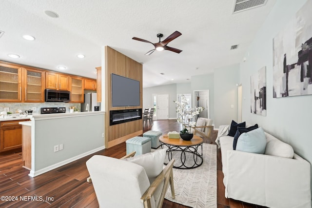 living room with a textured ceiling, vaulted ceiling, dark hardwood / wood-style floors, and ceiling fan