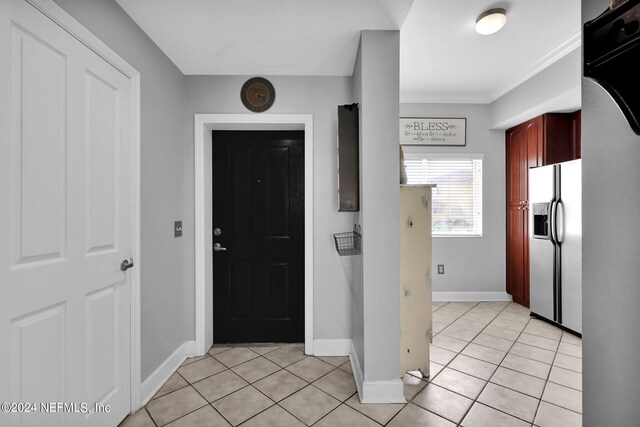 foyer entrance with light tile patterned floors and crown molding