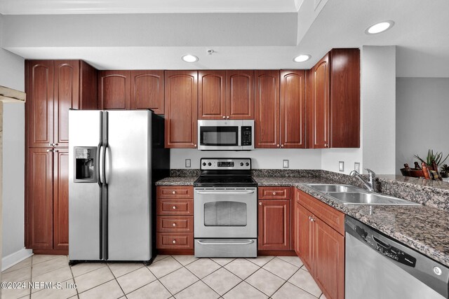 kitchen with dark stone counters, appliances with stainless steel finishes, sink, and light tile patterned flooring