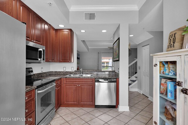 kitchen featuring appliances with stainless steel finishes, light tile patterned floors, dark stone countertops, and ornamental molding