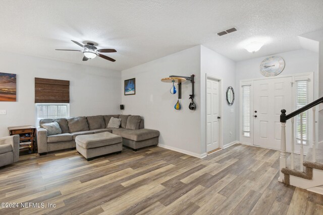 living room with ceiling fan, vaulted ceiling, a textured ceiling, and hardwood / wood-style floors