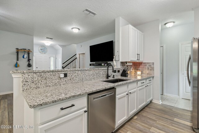 kitchen featuring white cabinets, sink, stainless steel appliances, light stone countertops, and light hardwood / wood-style floors