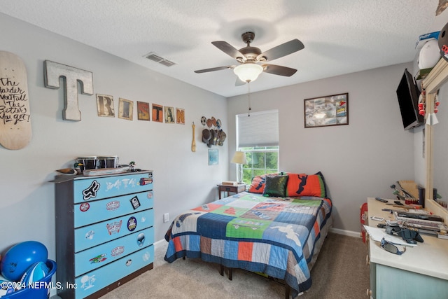 carpeted bedroom with ceiling fan and a textured ceiling