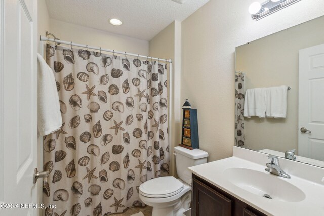 bathroom with a textured ceiling, walk in shower, vanity, and toilet