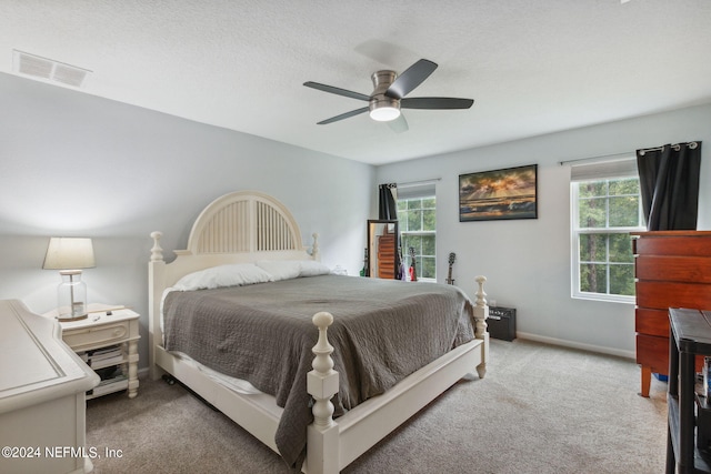 carpeted bedroom with multiple windows, a textured ceiling, and ceiling fan