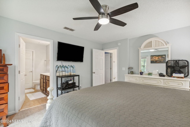 bedroom with light carpet, ceiling fan, ensuite bathroom, and a textured ceiling