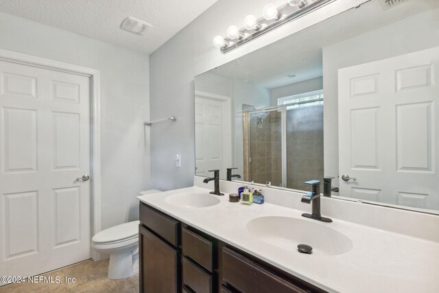 bathroom featuring vanity, a textured ceiling, toilet, and an enclosed shower