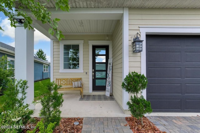 view of exterior entry featuring a garage and a porch