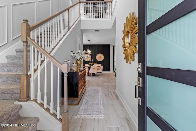 staircase featuring a high ceiling, wood-type flooring, and a chandelier