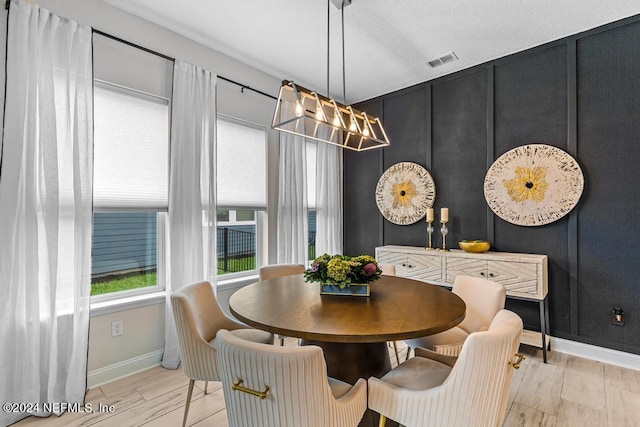 dining space featuring a textured ceiling and light hardwood / wood-style flooring