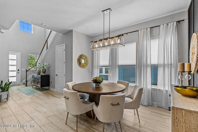 dining room with a textured ceiling, a healthy amount of sunlight, a chandelier, and light hardwood / wood-style floors