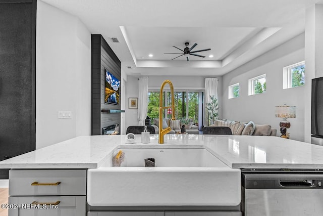 kitchen featuring dishwasher, a fireplace, a tray ceiling, and ceiling fan