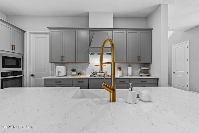 kitchen featuring black microwave, light stone countertops, and stainless steel oven