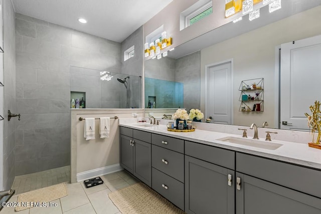 bathroom with tile patterned floors, tiled shower, and vanity