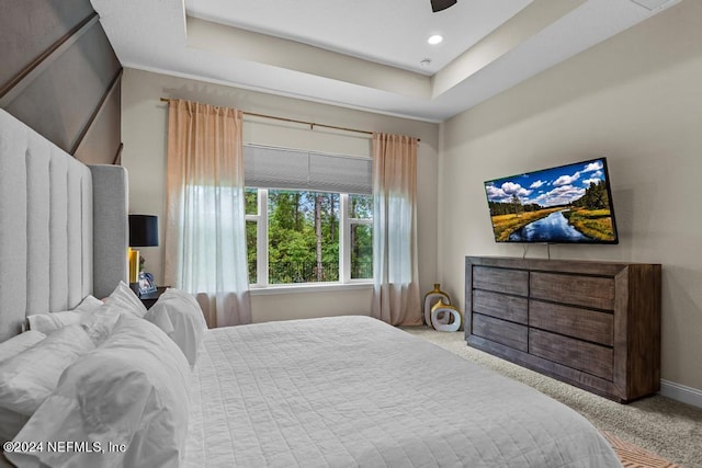 bedroom featuring a raised ceiling, ceiling fan, and light colored carpet