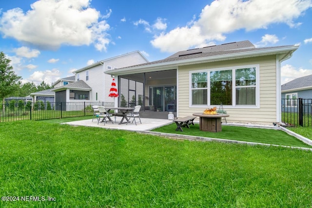 back of property with a yard, a patio area, and an outdoor fire pit