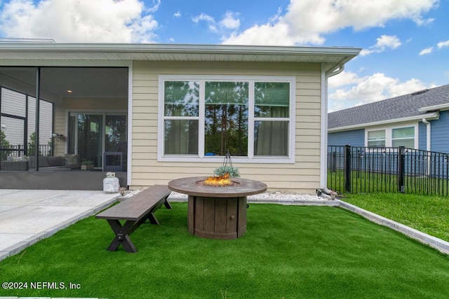 rear view of property with a fire pit, a yard, and a patio