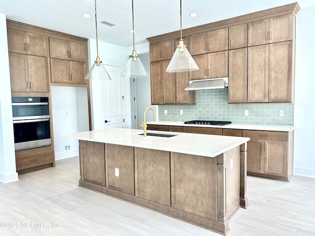 kitchen with gas stovetop, a sink, under cabinet range hood, double oven, and backsplash