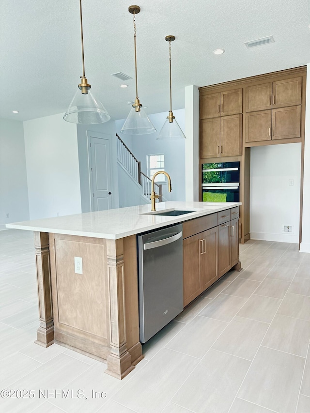 kitchen with light countertops, an island with sink, stainless steel dishwasher, hanging light fixtures, and a sink