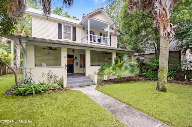 front of property featuring a porch, ceiling fan, a front lawn, and a balcony