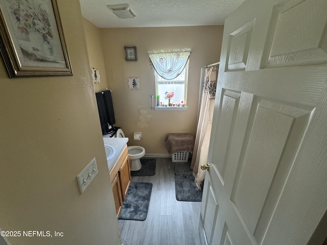 7071 Luke St, Jacksonville, FL 32210 - bathroom with a textured ceiling, visible vents, toilet, wood finished floors, and vanity