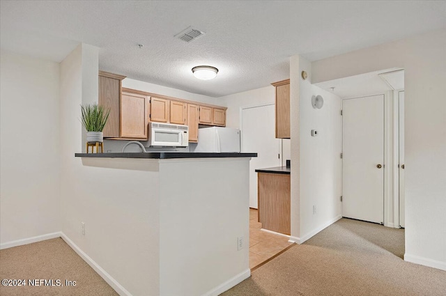 kitchen with kitchen peninsula, white appliances, and light colored carpet