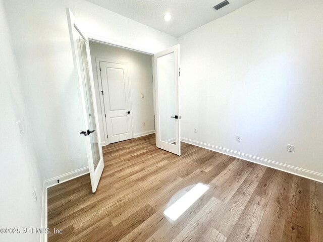 63 Oakmoss Dr, Saint Johns, FL 32259 - unfurnished bedroom with baseboards, french doors, wood finished floors, and visible vents