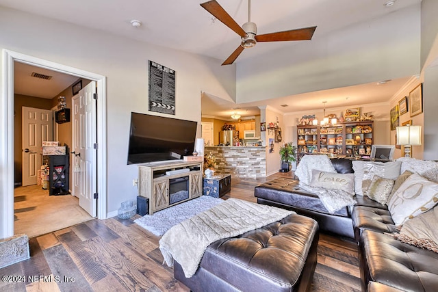 living room featuring a fireplace, ceiling fan with notable chandelier, ornamental molding, and wood-type flooring