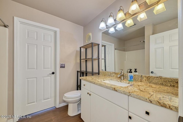 bathroom with toilet, vanity, hardwood / wood-style floors, and walk in shower