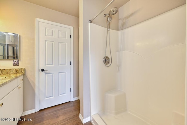 bathroom featuring hardwood / wood-style flooring, vanity, and a shower