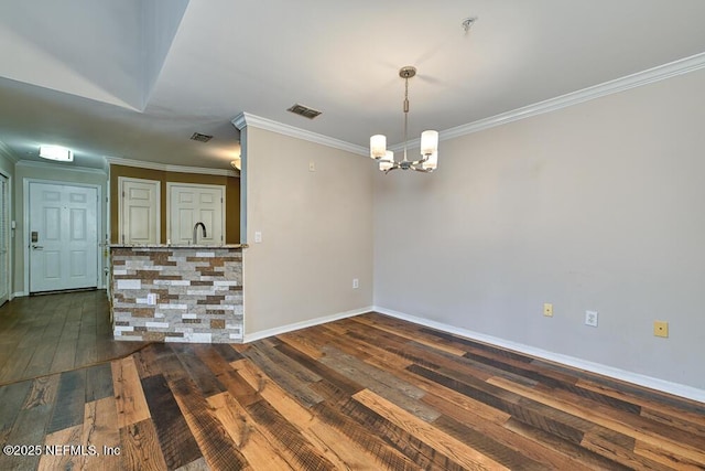 spare room with sink, ornamental molding, dark hardwood / wood-style floors, and a notable chandelier